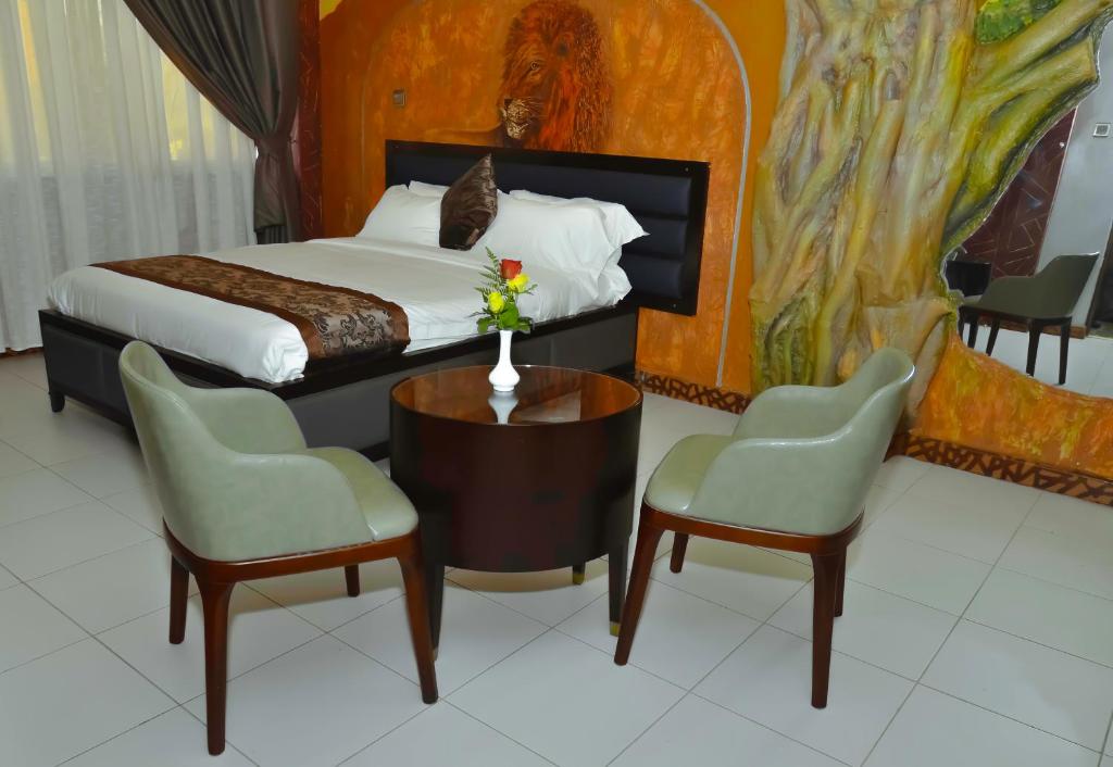 a bedroom with a bed and two chairs and a table at Lagos Hotel in Nairobi