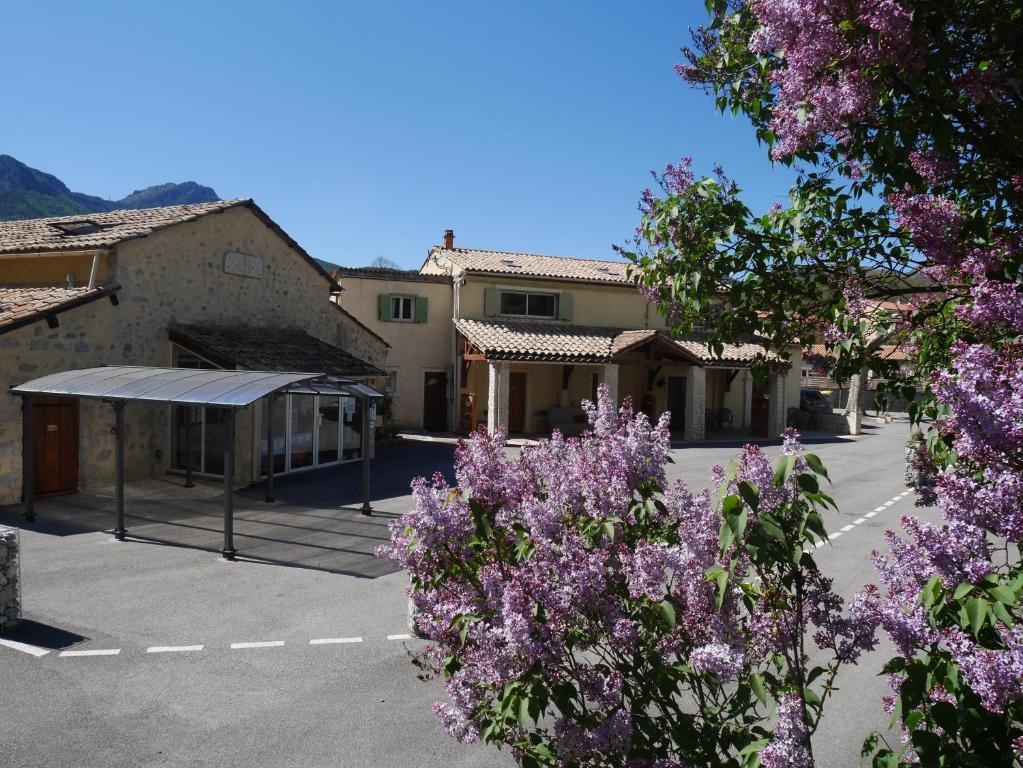 un estacionamiento con flores púrpuras frente a un edificio en L'Oustaou Castellane, en Castellane