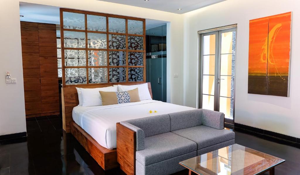 a bedroom with a bed and a couch and a window at Sun Island Boutique Villas & Spa Seminyak in Seminyak