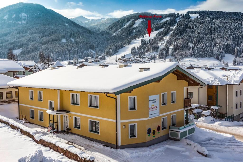 een geel gebouw met sneeuw op het dak bij Sunside in Flachau