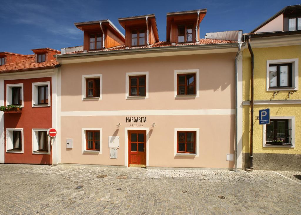 a white building with a red door on a street at Villa Margarita in Český Krumlov