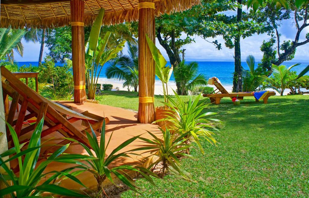 a resort with a bench and the ocean in the background at Les Tipaniers Lodge in Sainte Marie