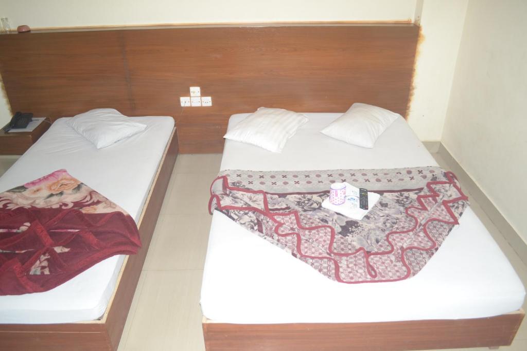 Zwei Betten in einem kleinen Zimmer mit weißen Laken in der Unterkunft Dynamic SH Resort in Cox's Bazar