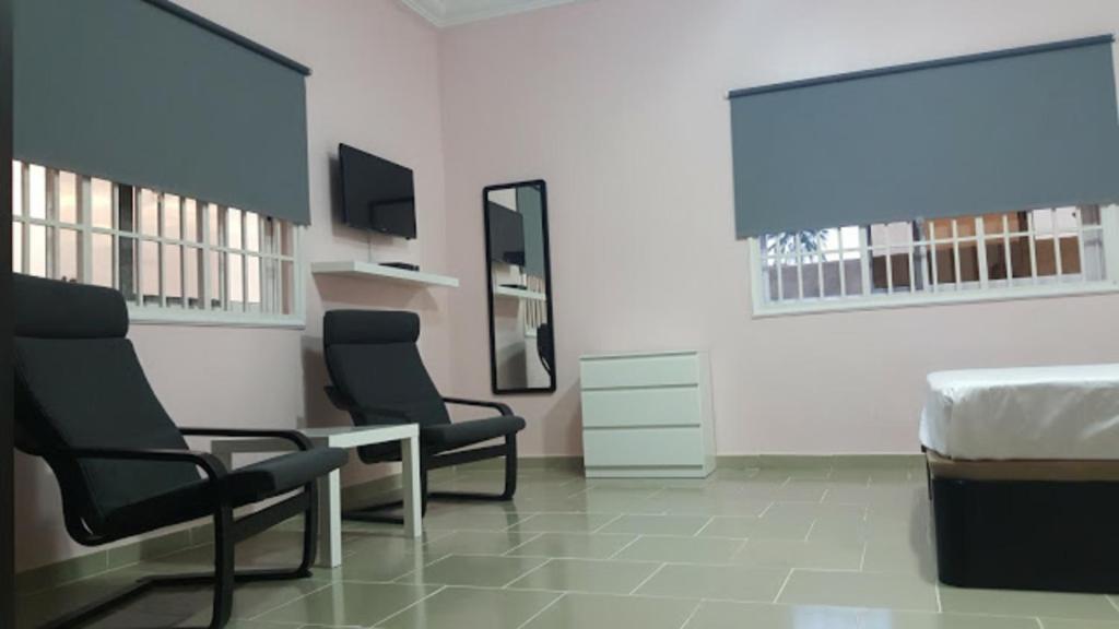 a room with two chairs and a bed and a desk at Muntala's Guest House in Hohoe