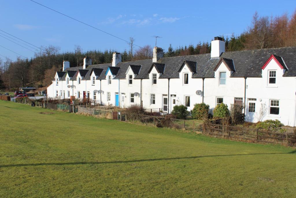 una fila de casas blancas con un campo verde en Crinan Canal Cottage No8, en Lochgilphead