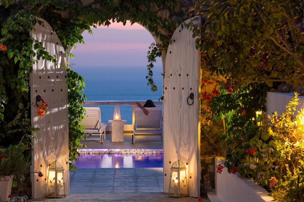 an archway leading to a pool with a view of the ocean at Athermi Suites - Adults Only in Megalochori