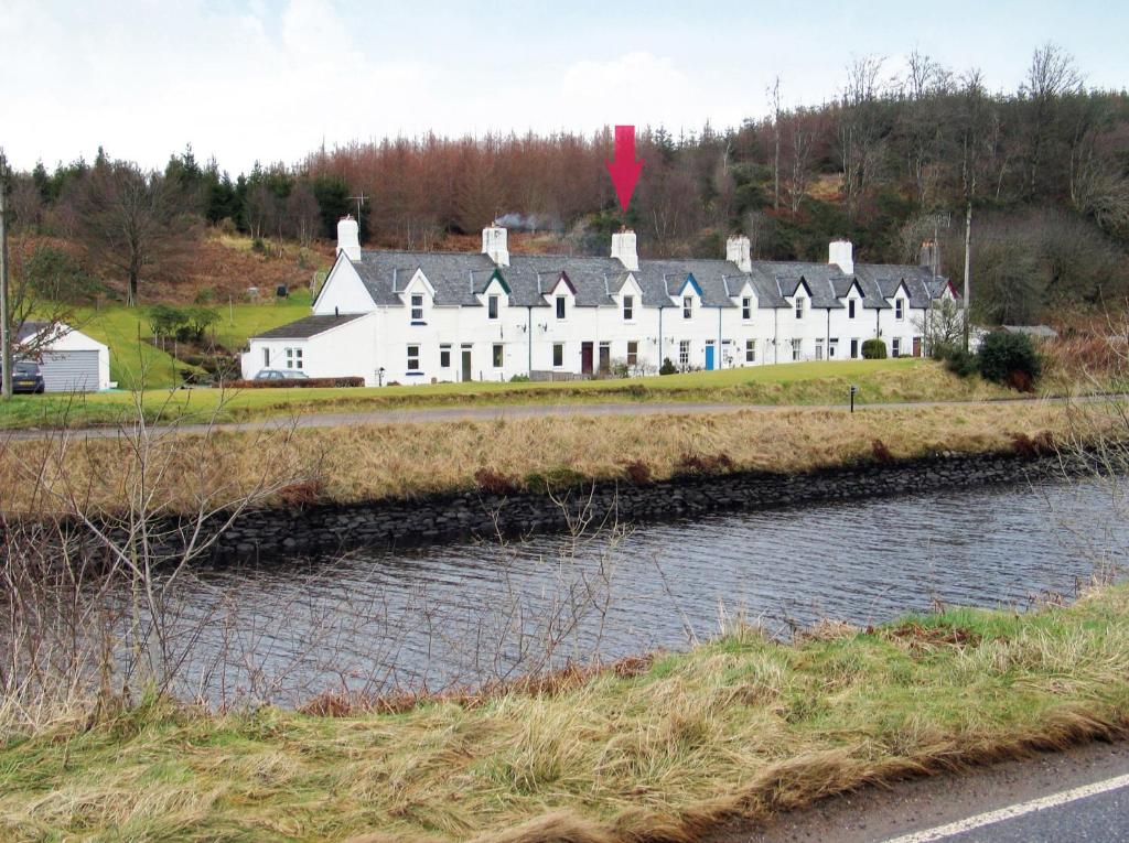 a large white house on a hill next to a river at Crinan Canal Cottage in Lochgilphead