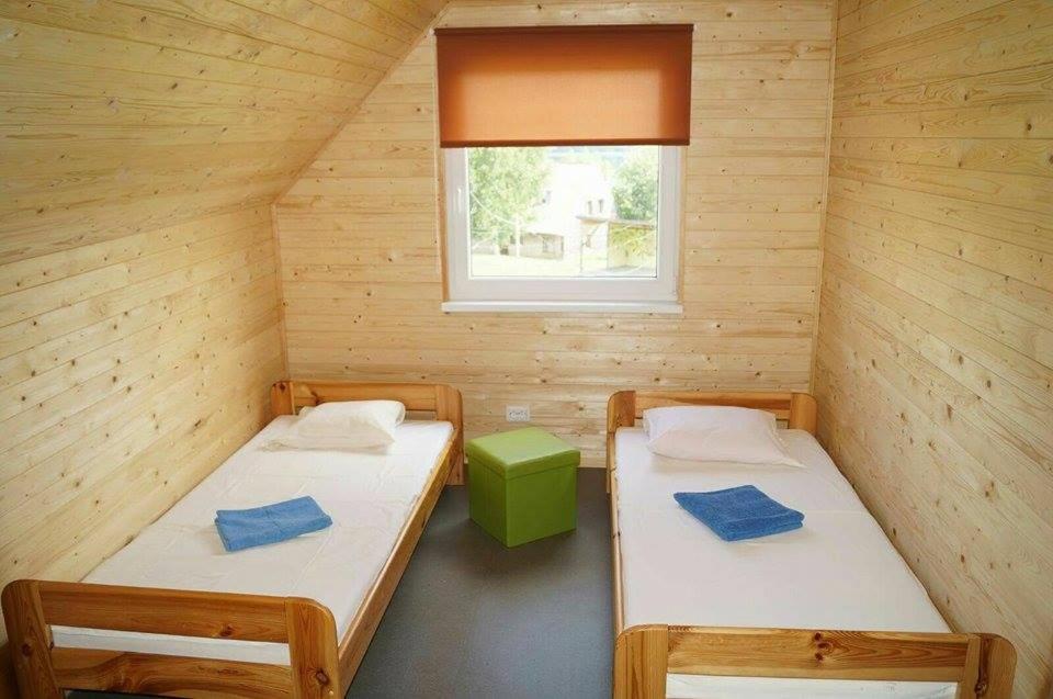 two beds in a wooden room with a window at Mežezera stāsts in Pļaviņas