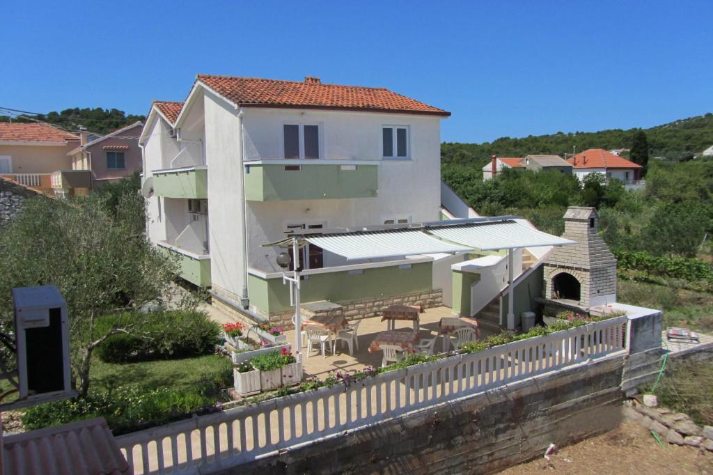 une grande maison blanche avec une clôture devant elle dans l'établissement Apartments Lonić, à Kukljica