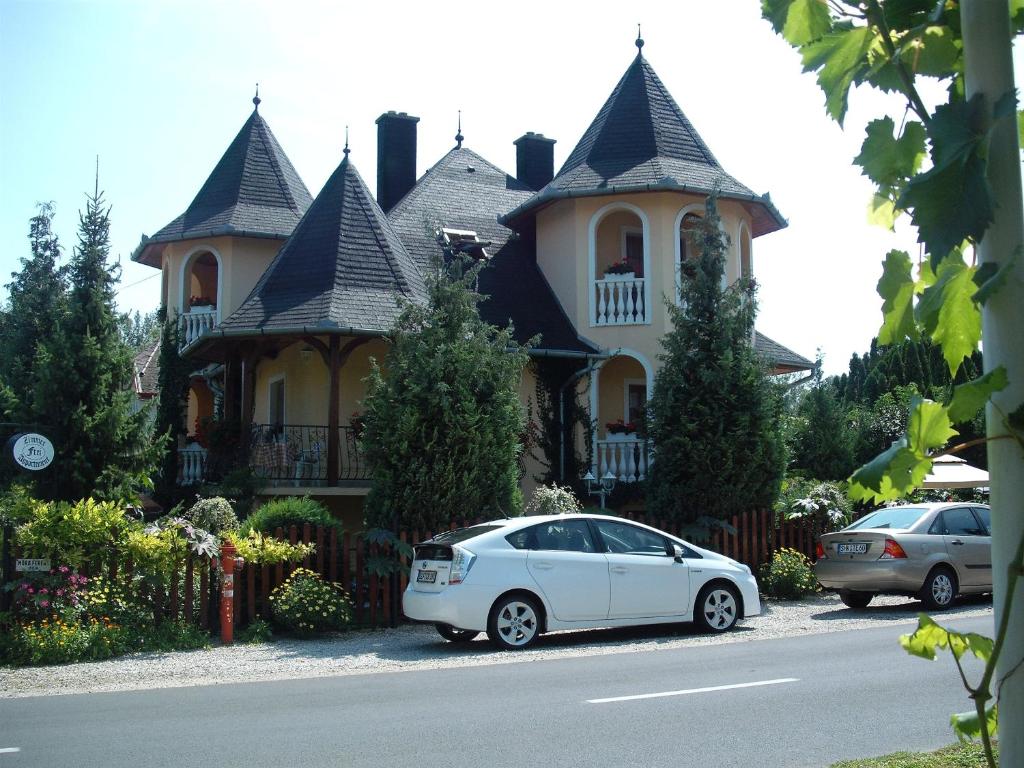 une voiture blanche garée devant une grande maison dans l'établissement Ilona Kis Kastély Panzió, à Keszthely