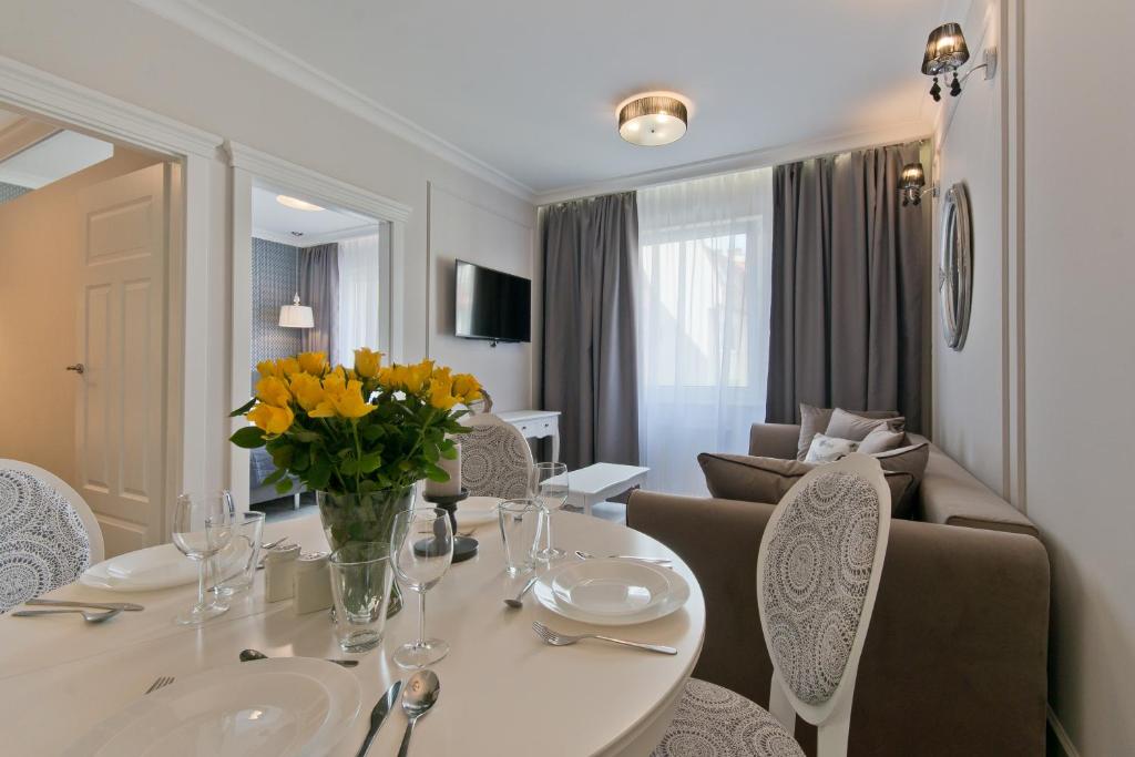 Apartamenty Gdańsk EU - Sopot Apartamenty في سوبوت: غرفة طعام مع طاولة مع زهور صفراء عليها