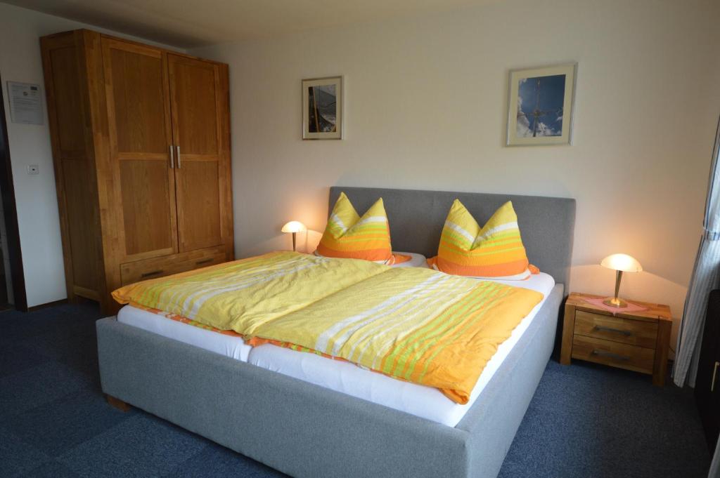 a bedroom with a large bed with yellow and orange pillows at Haus Hannover in Carolinensiel