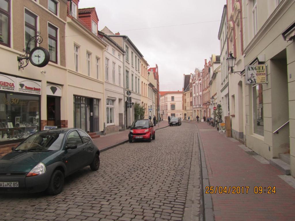 eine Straße mit Autos auf einer Kopfsteinpflasterstraße in der Unterkunft Altstadt Ferienwohnung in Wismar