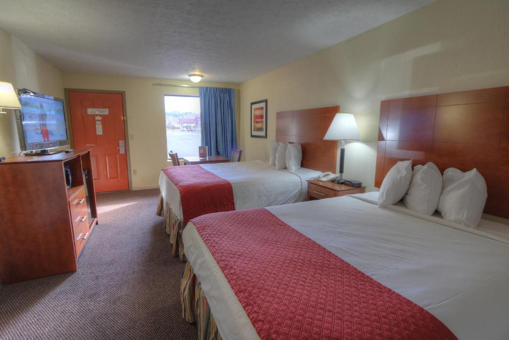 a hotel room with two beds and a flat screen tv at Days Inn By Wyndham Pigeon Forge South in Pigeon Forge