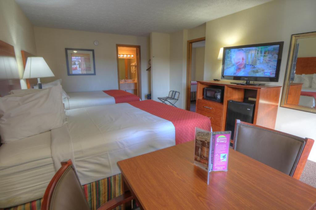 a hotel room with a bed and a table and a television at Days Inn By Wyndham Pigeon Forge South in Pigeon Forge