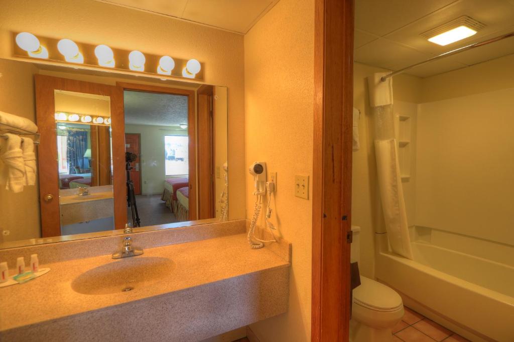a bathroom with a sink and a mirror and a toilet at Days Inn By Wyndham Pigeon Forge South in Pigeon Forge