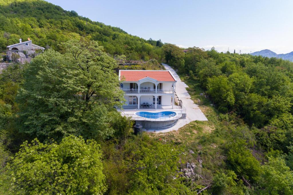 an aerial view of a house on a hill with trees at Whitehouse Villa in Virpazar