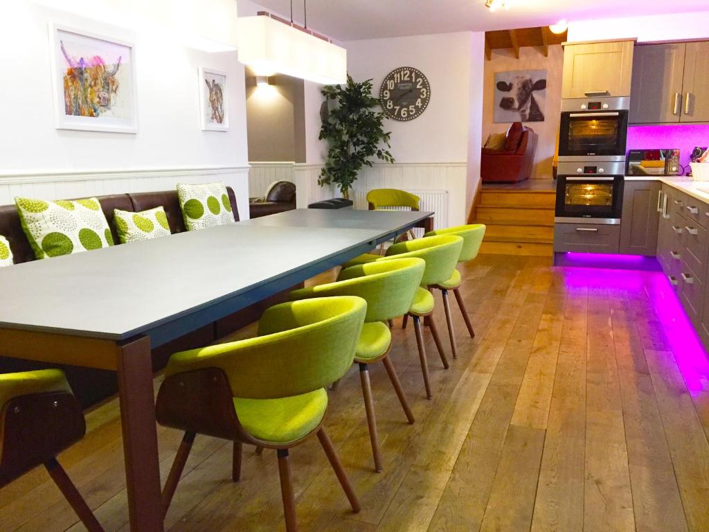 a dining room with a long table and green chairs at Hillview Cottage in Glenlivet