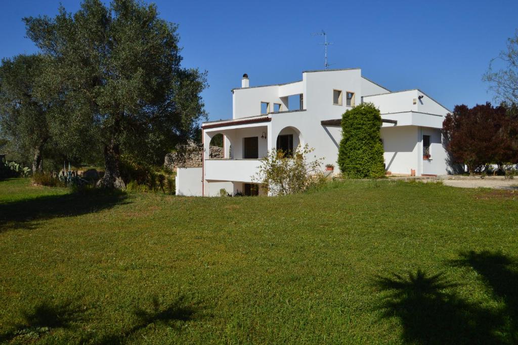 ein weißes Haus auf einem grünen Feld in der Unterkunft Casa De Luca in Arnesano