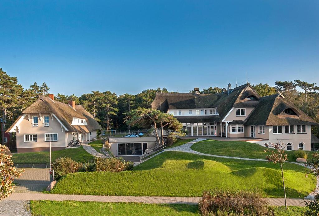 a large white house with a grass yard at Strandhaus Ahrenshoop in Ahrenshoop