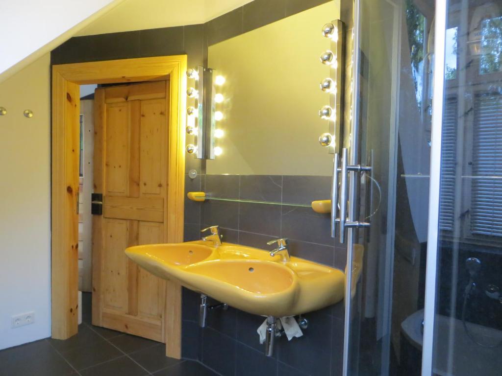 a bathroom with a yellow sink and a mirror at Fischerhaus am See in Berlin