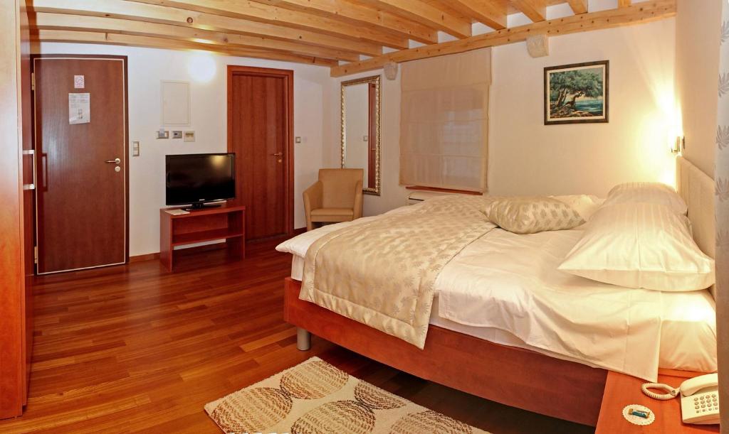 a bedroom with a large bed and a television at Hotel Monika in Trogir