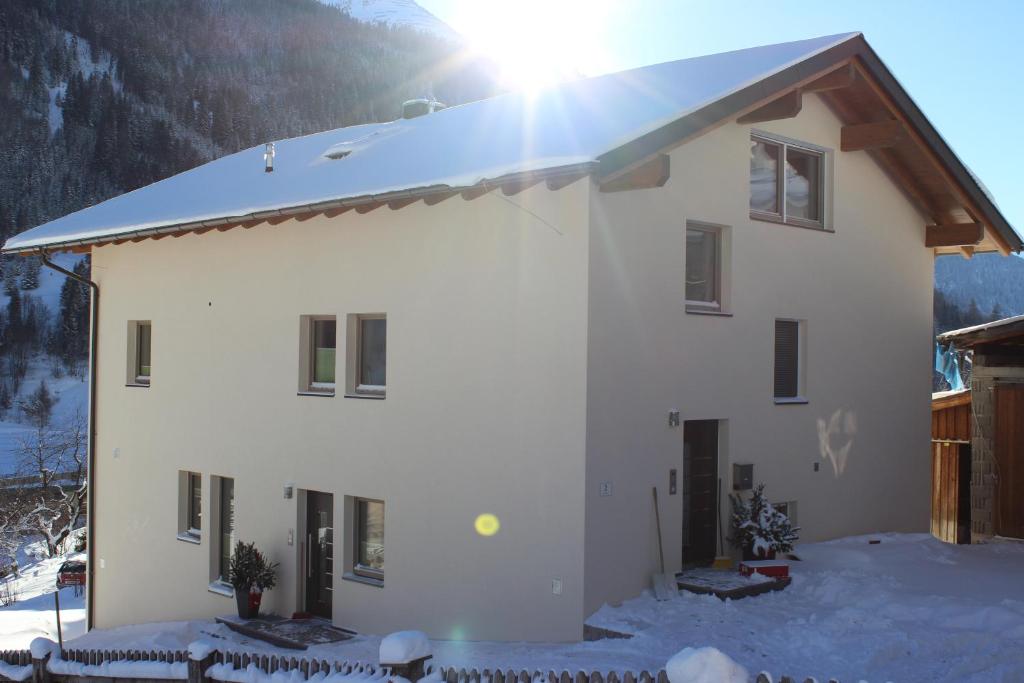 a house in the snow with the sun shining at Haus Bichali in Sankt Anton am Arlberg