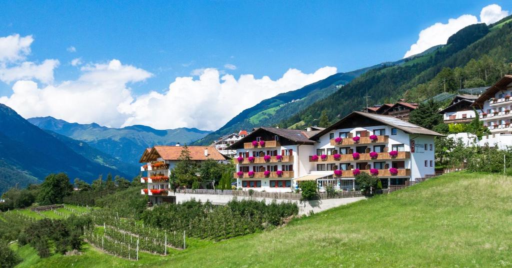 a group of buildings on a hill with mountains at Pension Grafenau in Schenna