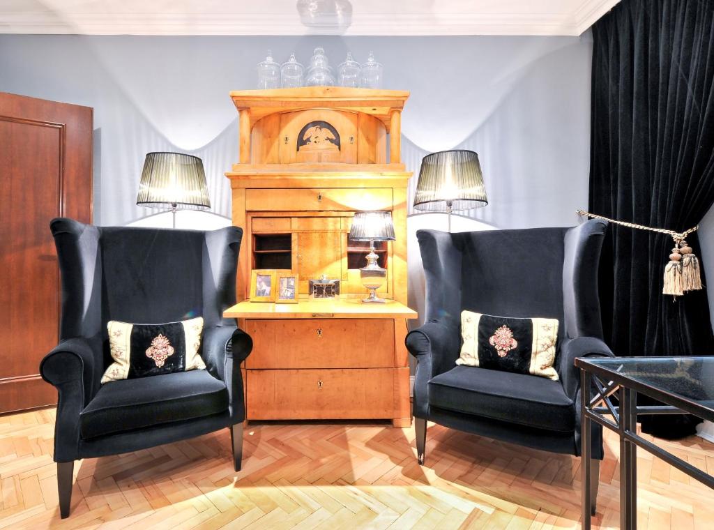 two chairs in a living room with a table and a clock at Hotel Sir & Lady Astor in Düsseldorf