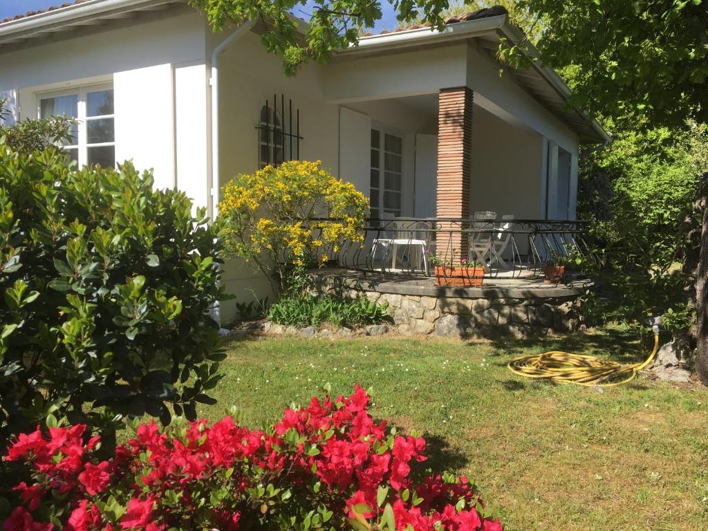 une maison avec des fleurs rouges dans la cour dans l'établissement Villa Pagnol, à Andernos-les-Bains