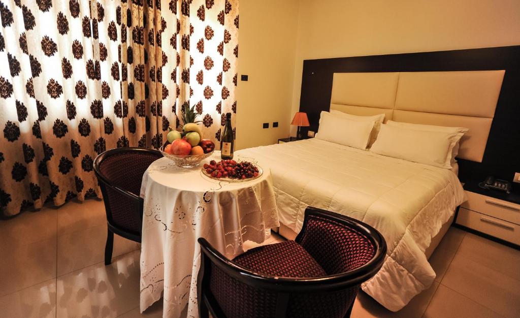 sypialnia z łóżkiem i stołem z owocami w obiekcie Hotel Vila e Arte City Center w Tiranie