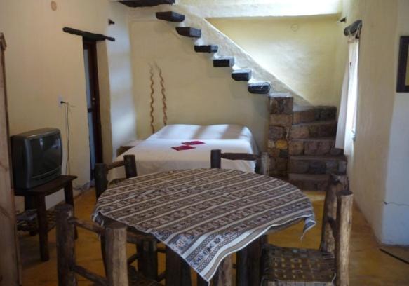 a room with a bed and a staircase with a tv at Piedramora Tilcara in Tilcara