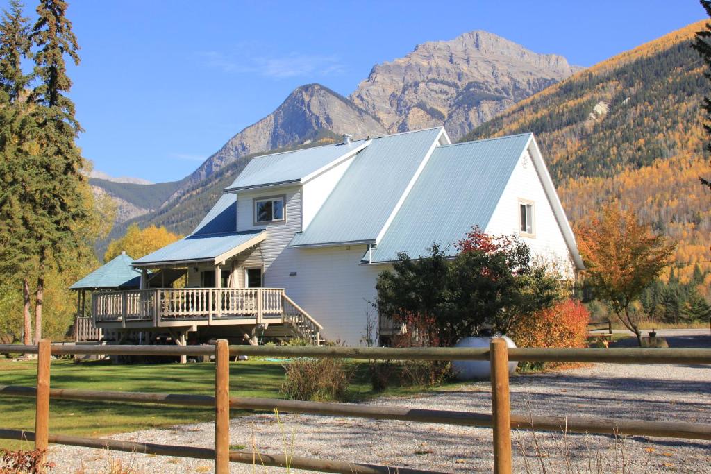a white house with a porch and mountains in the background at Bear Paw Lodge in Golden