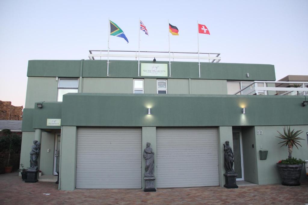 two flags on top of a building with two garage doors at Secret Garden Guesthouse in Bloubergstrand