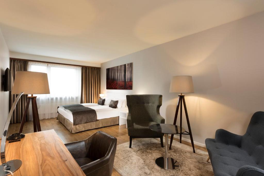 a hotel room with a bed and a table and chairs at Wyndham Stuttgart Airport Messe in Stuttgart