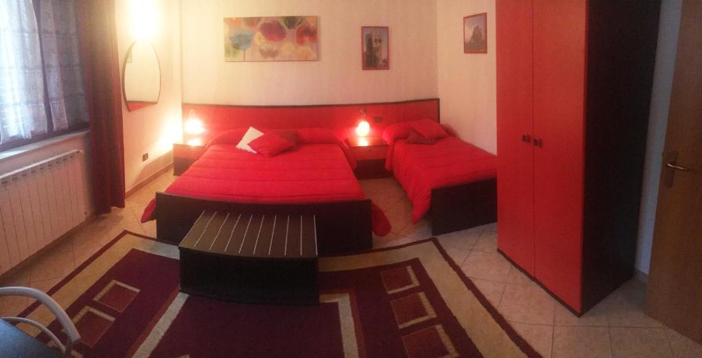 sypialnia z 2 łóżkami z czerwoną pościelą i stołem w obiekcie B&B Villa Giglio w mieście Catanzaro
