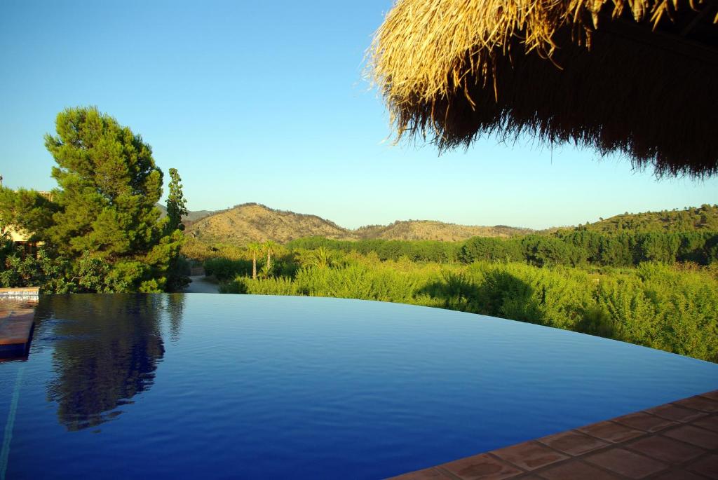 une grande piscine d'eau avec des montagnes en arrière-plan dans l'établissement Masía Durbá B&B, à Castellnovo