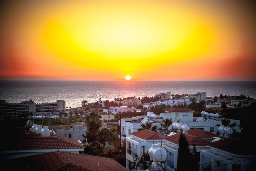 a sunset over a city and the ocean at Julipapas Gardens in Paphos