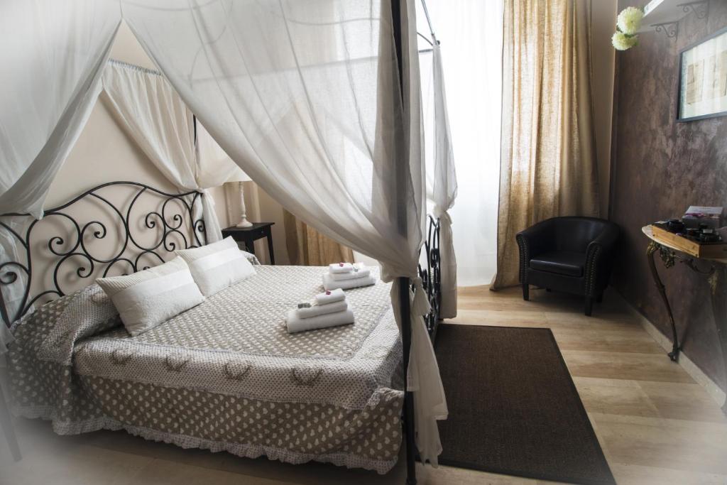 ローマにあるバチカン ルームズ アコモデーションのベッドルーム1室(天蓋付きベッド1台、椅子、デスク付)