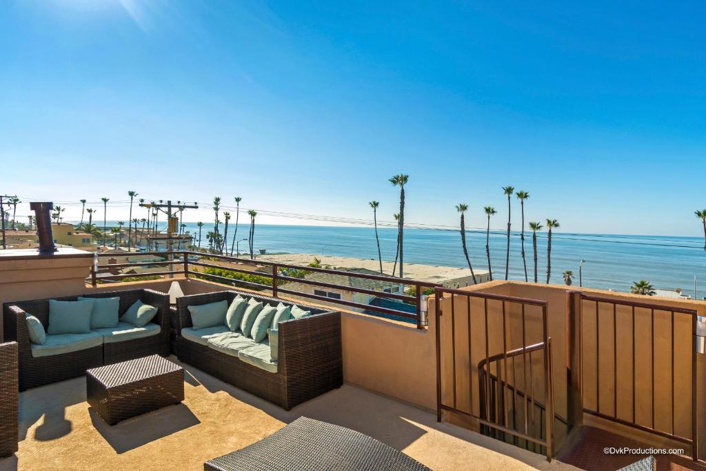 a balcony with a couch and chairs and the beach at Ocean View Steps to Beach M-C in Oceanside