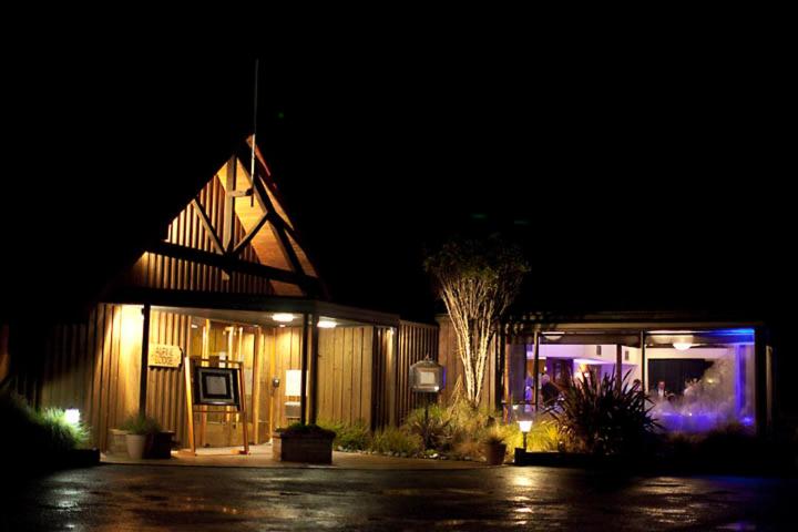 ein beleuchtetes Gebäude in der Nacht mit einem Baum davor in der Unterkunft Alpine Lodge in Saint Arnaud