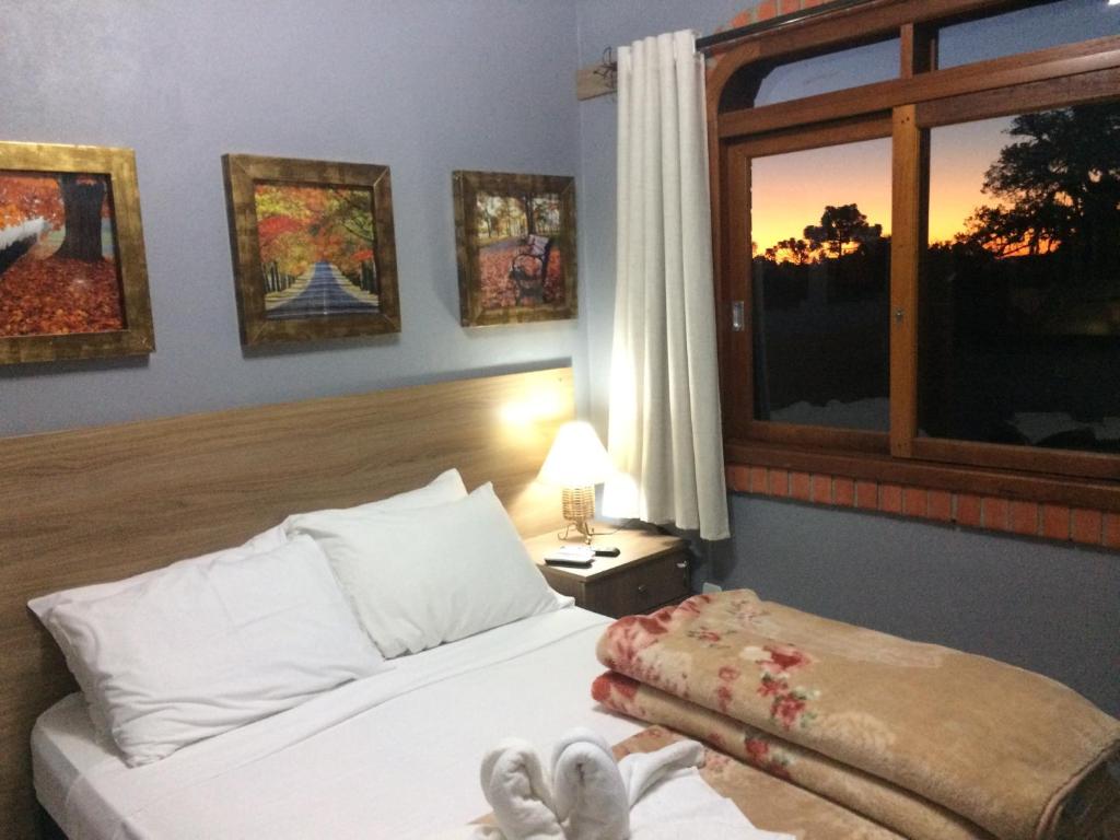 Un dormitorio con una cama y una ventana con dos zapatos. en Residencial Quatro Estações, en Canela