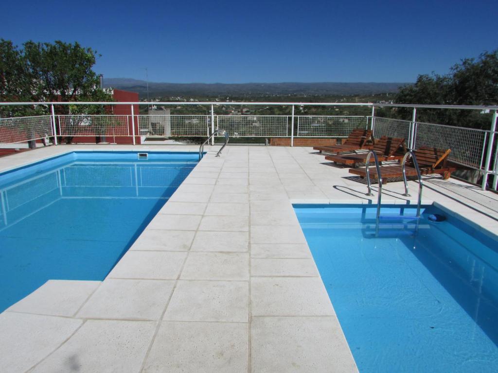 a swimming pool on a roof with chairs around it at La Villa Inn in Villa Carlos Paz