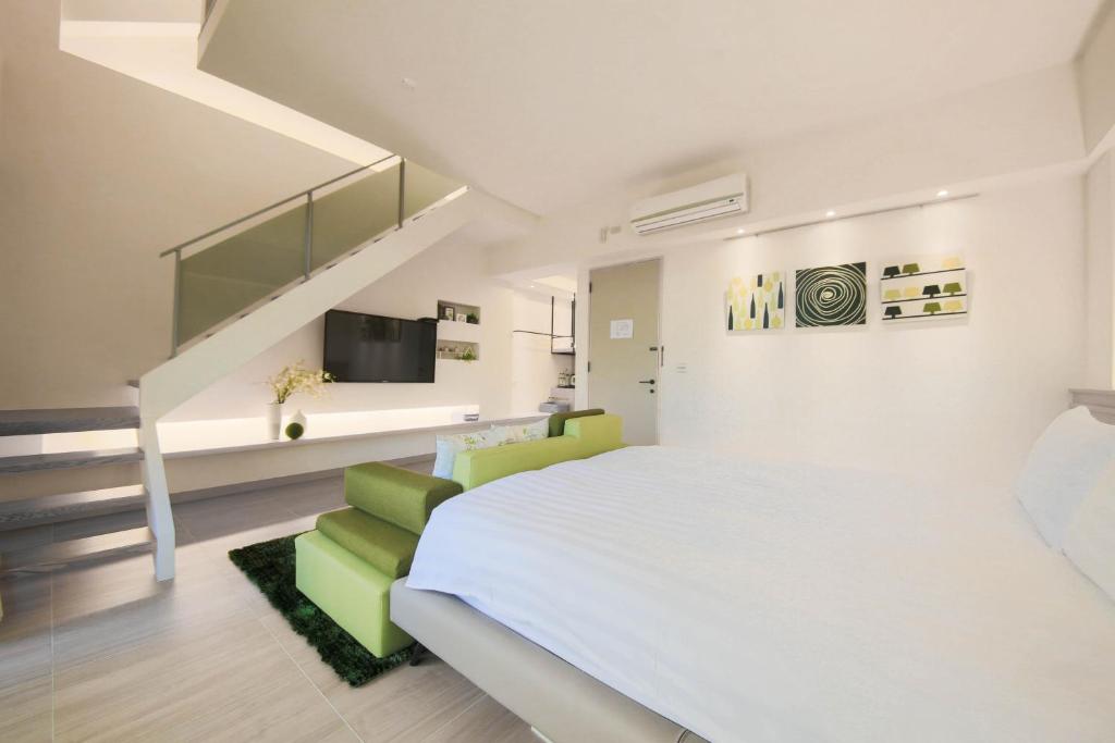 a bedroom with a white bed and a green chair at Liu Yuan Green Villa in Taitung City