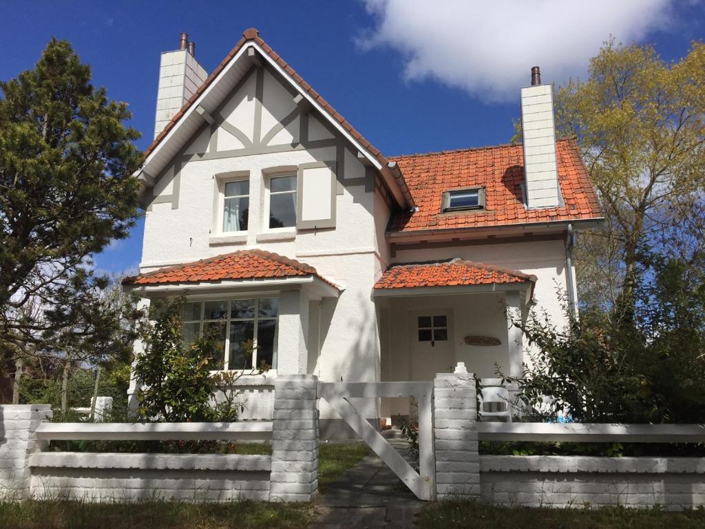 une maison blanche avec une clôture devant elle dans l'établissement Vakantiehuis Strandpieper, à Oostduinkerke