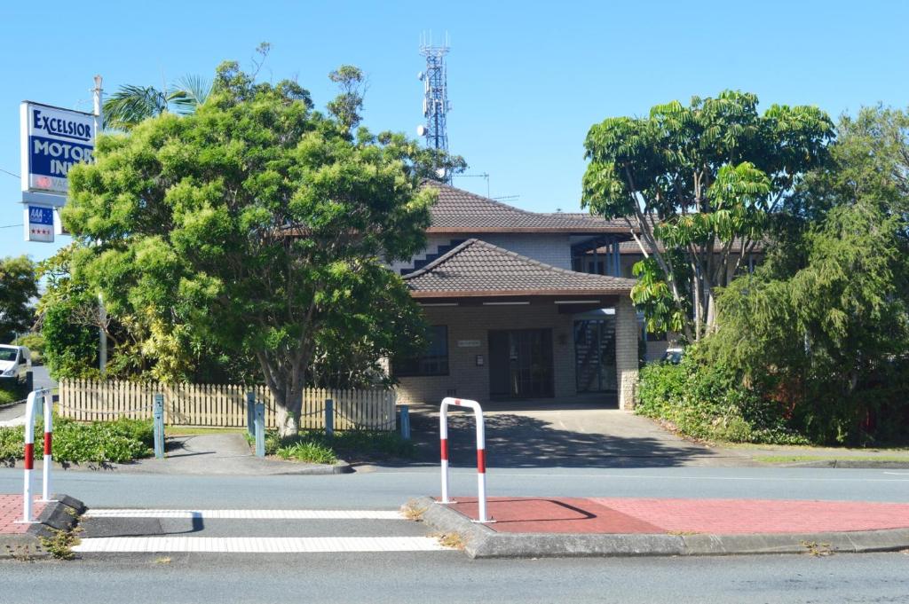 una calle con un edificio con un cartel delante en Excelsior Motor Inn en Port Macquarie