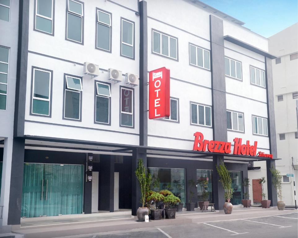 a large white building with a red hotel sign at Brezza Hotel Sitiawan in Sitiawan