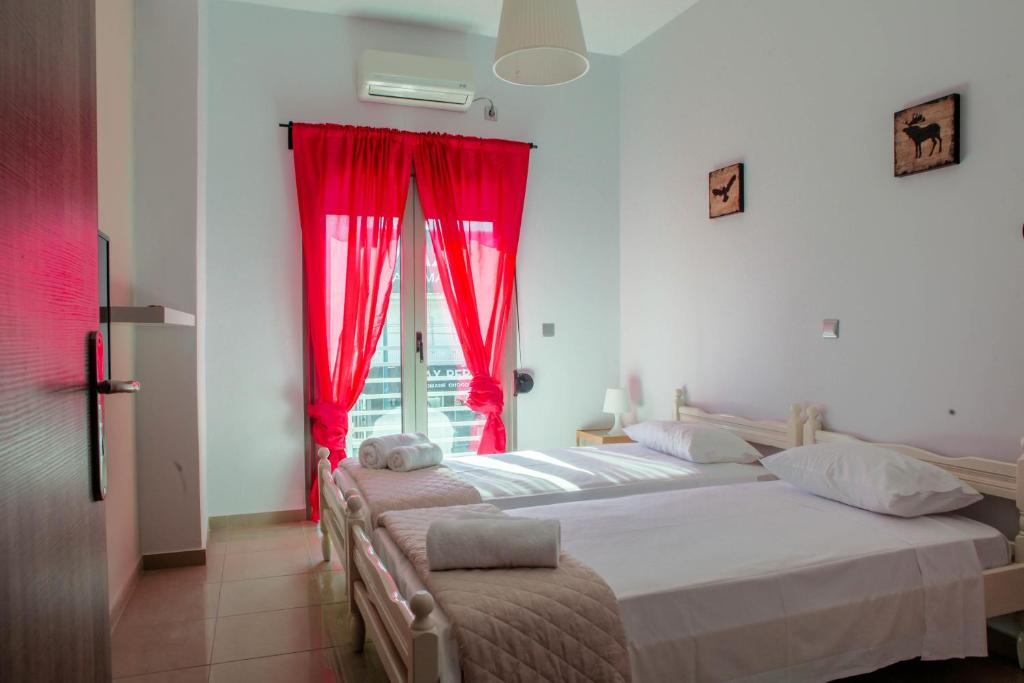 two beds in a room with red curtains and a window at Lak Peristeri Homes in Athens