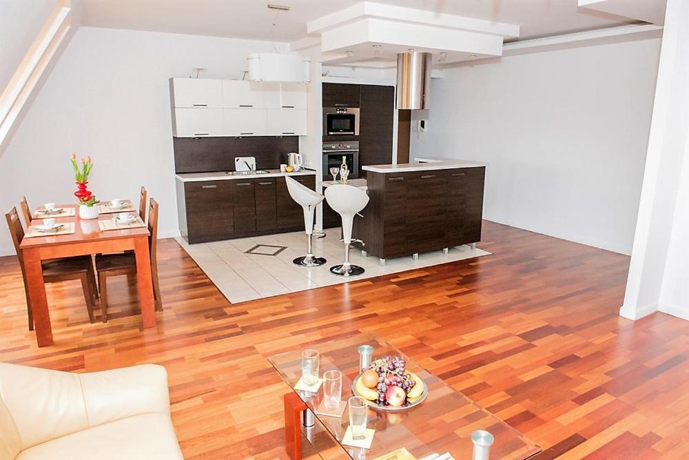 a kitchen and living room with a wooden floor at 3-Pokojowy Apartament Villa Park - Top Location in Olsztyn