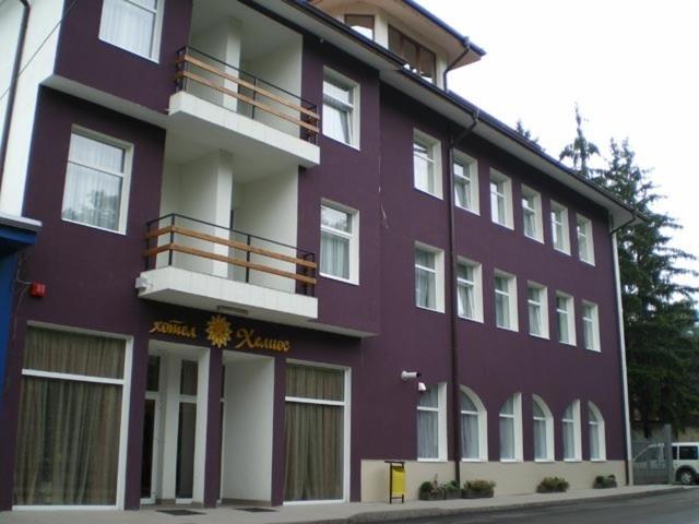 a purple building with a balcony on a street at Family Hotel Helios in Sevlievo